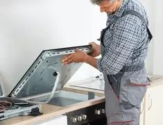 Appliance repair technician installing a built-in cooktop in Pittsburgh, PA