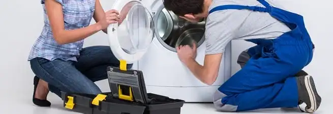 Washer repair technician inspecting a front-load washing machine with tools in Pittsburgh, PA