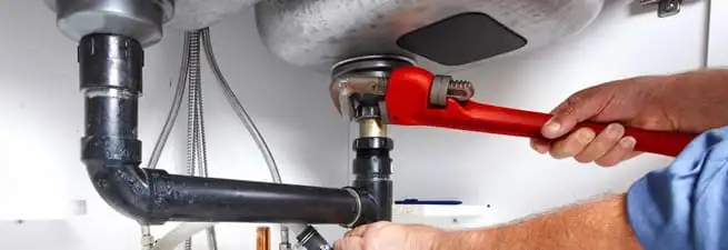 Garbage disposal repair technician tightening the sink drain and disposal connection in Pittsburgh, PA