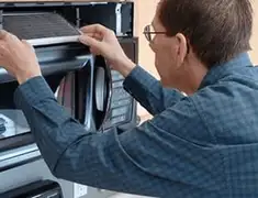 Appliance repair technician replacing a microwave vent filter in Pittsburgh, PA