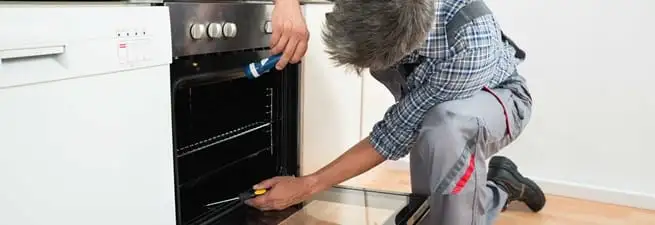 Oven repair technician inspecting and servicing an electric oven in Pittsburgh, PA