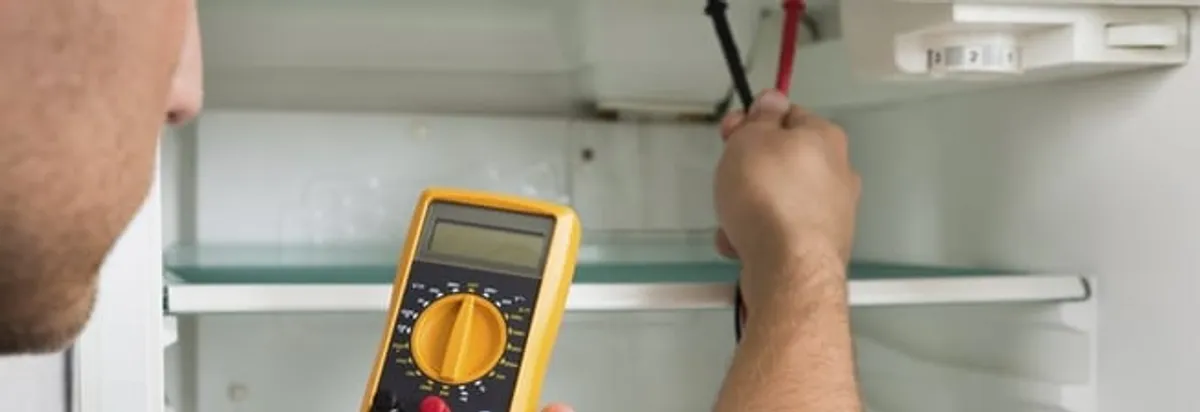 Refrigerator repair technician testing electrical components with a multimeter in Pittsburgh, PA