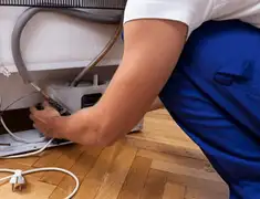 Appliance repair technician fixing refrigerator water line and connections in Pittsburgh, PA