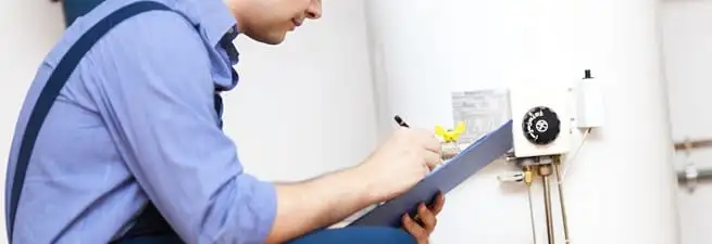 Water heater repair technician inspecting the unit and recording service notes in Pittsburgh, PA
